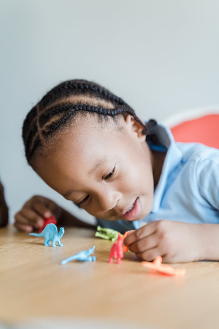 A child engaged in imaginative play with toy dinosaurs at a table.